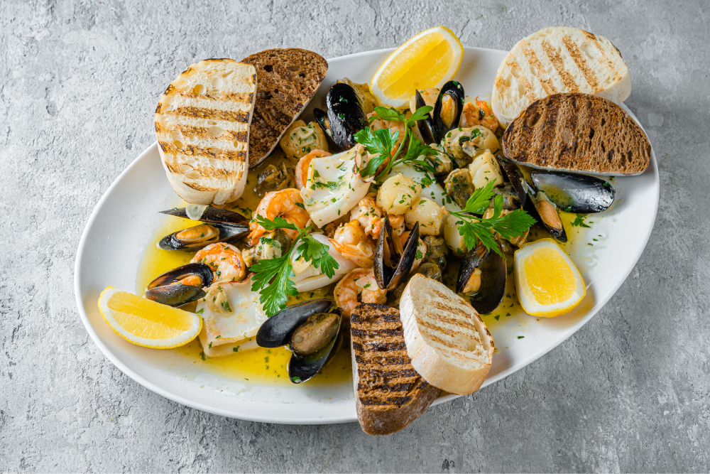 Ассорти из морепродуктов на сковородке с чесноком и зеленью