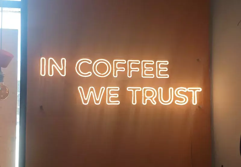 Неоновая надпись «In coffee we trust» на&nbsp;деревянной стене