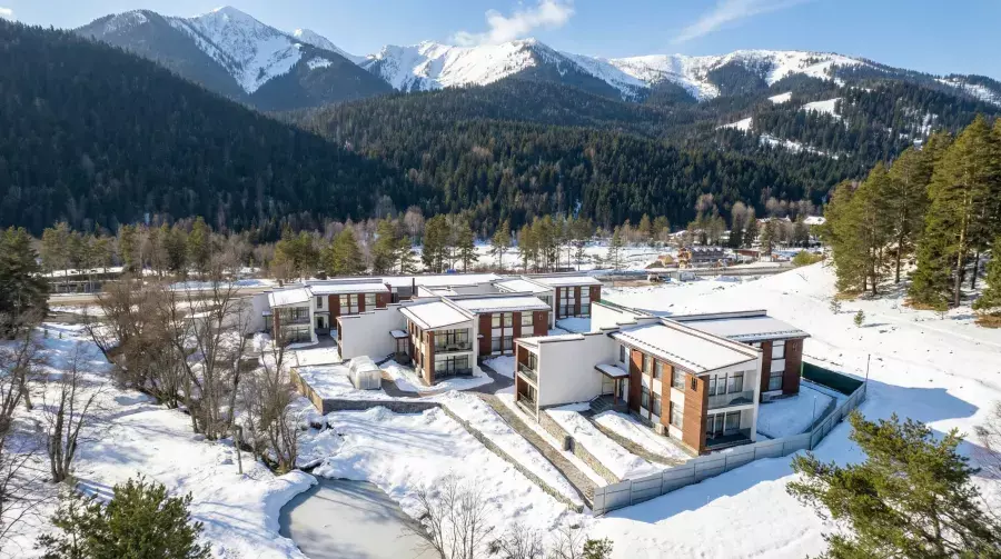 Корпуса отеля Premium Village Arkhyz среди заснеженного леса