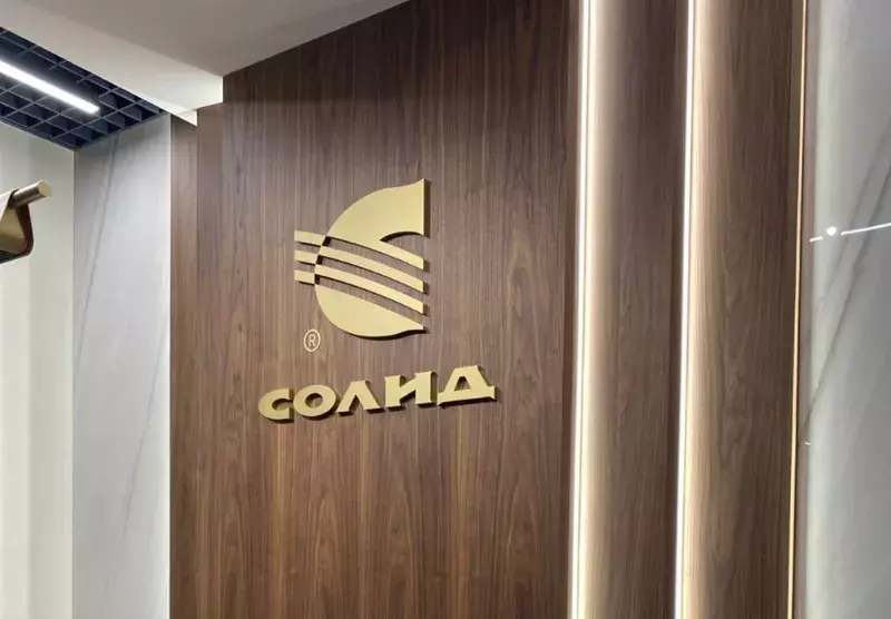 Золотой логотип «Солид» на&nbsp;деревянной панели