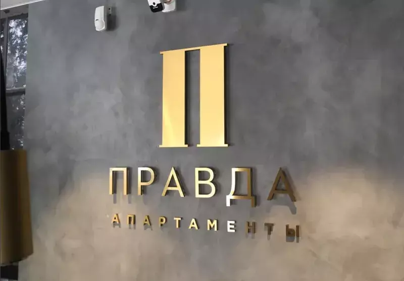 Золотой логотип «Правда апартаменты» на&nbsp;бетонной стене