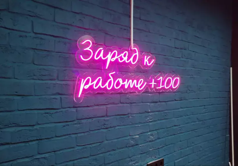Розовая неоновая надпись «Заряд к&nbsp;работе +100» на&nbsp;кирпичной стене