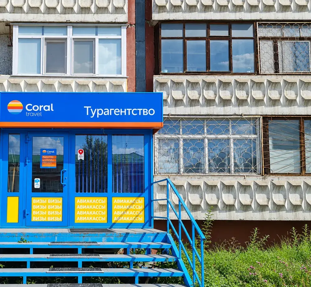 Вход в офис Coral Travel: синие ступени с перилами и вывеска над дверью