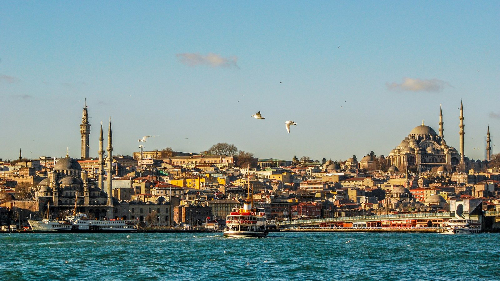 A ferry crossing the water in front of Eminönü, Istanbul, with the New Mosque, the Galata Bridge and the Süleymaniye Mosque on the hill