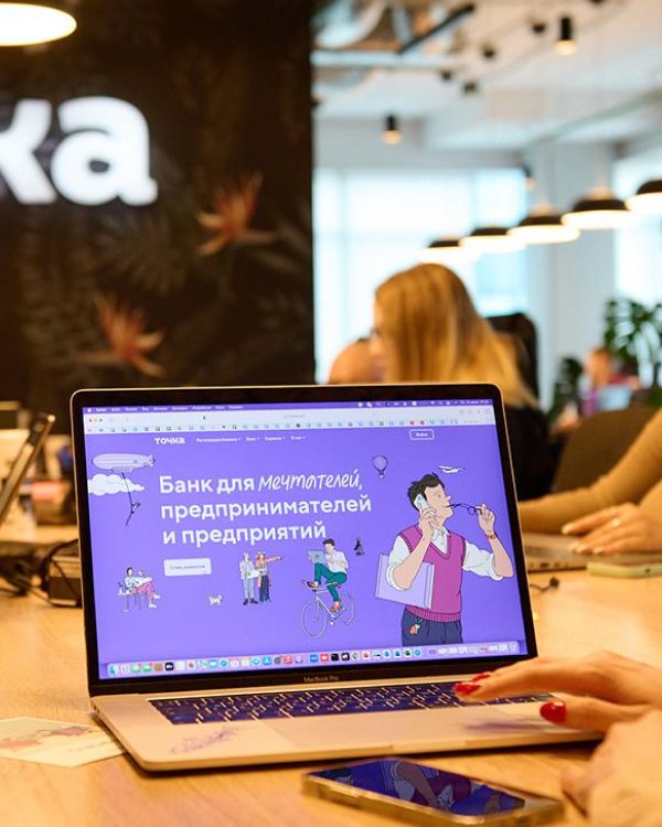 Сотрудница работает за ноутбуком с сайтом Точки в офисе банка