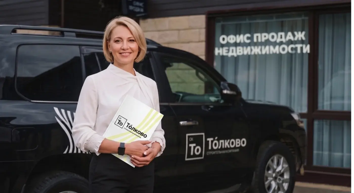 Представитель компании с фирменной папкой у офиса продаж