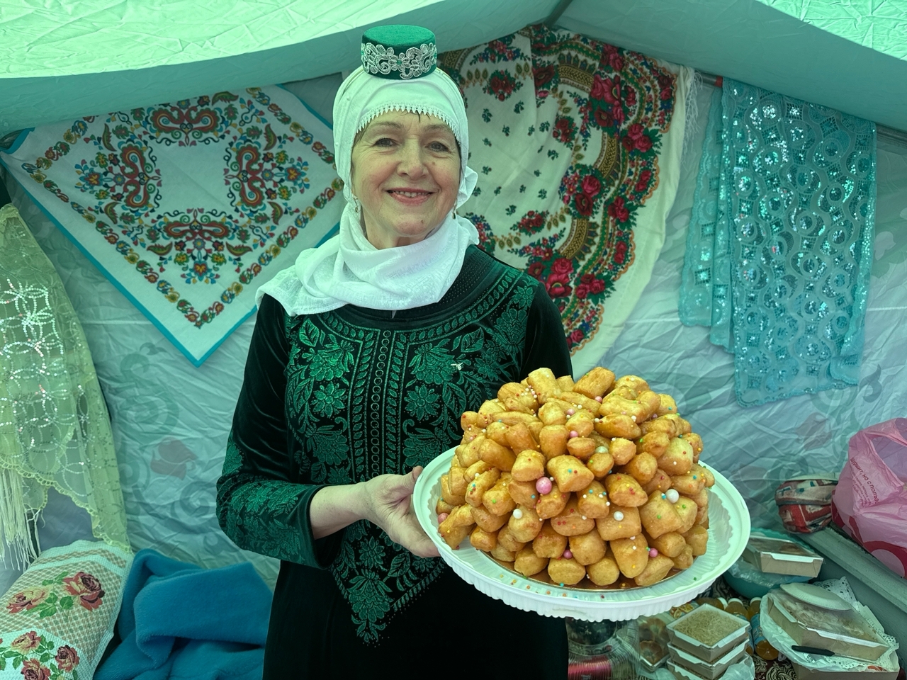 Татарская участница праздника с тарелкой традиционных эчпочмаков