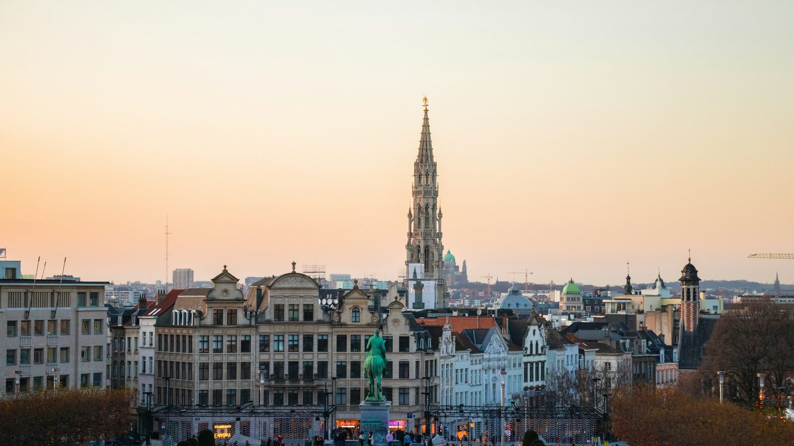 Brussels skyline at sunset seen from the Mont des Arts, with the Gothic spire of the Town Hall and an equestrian statue in front