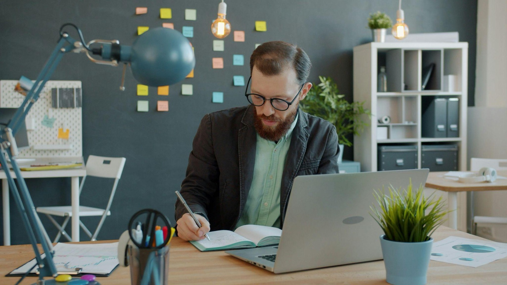 Founder writing a demo video script in a notebook next to a laptop
