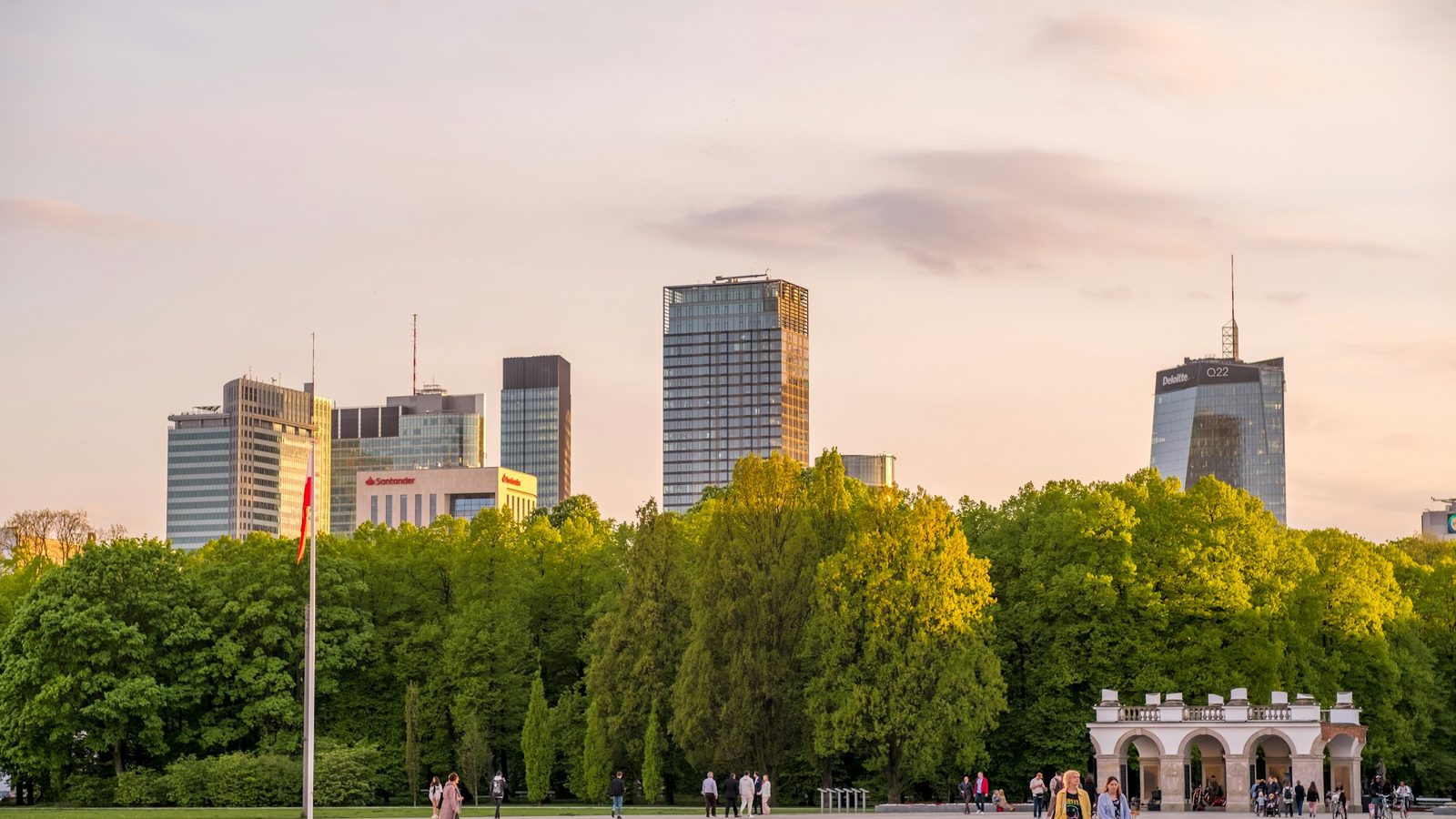 Office towers of central Warsaw rising behind the trees of the Saxon Garden, seen from Piłsudski Square with the Tomb of the Unknown Soldier