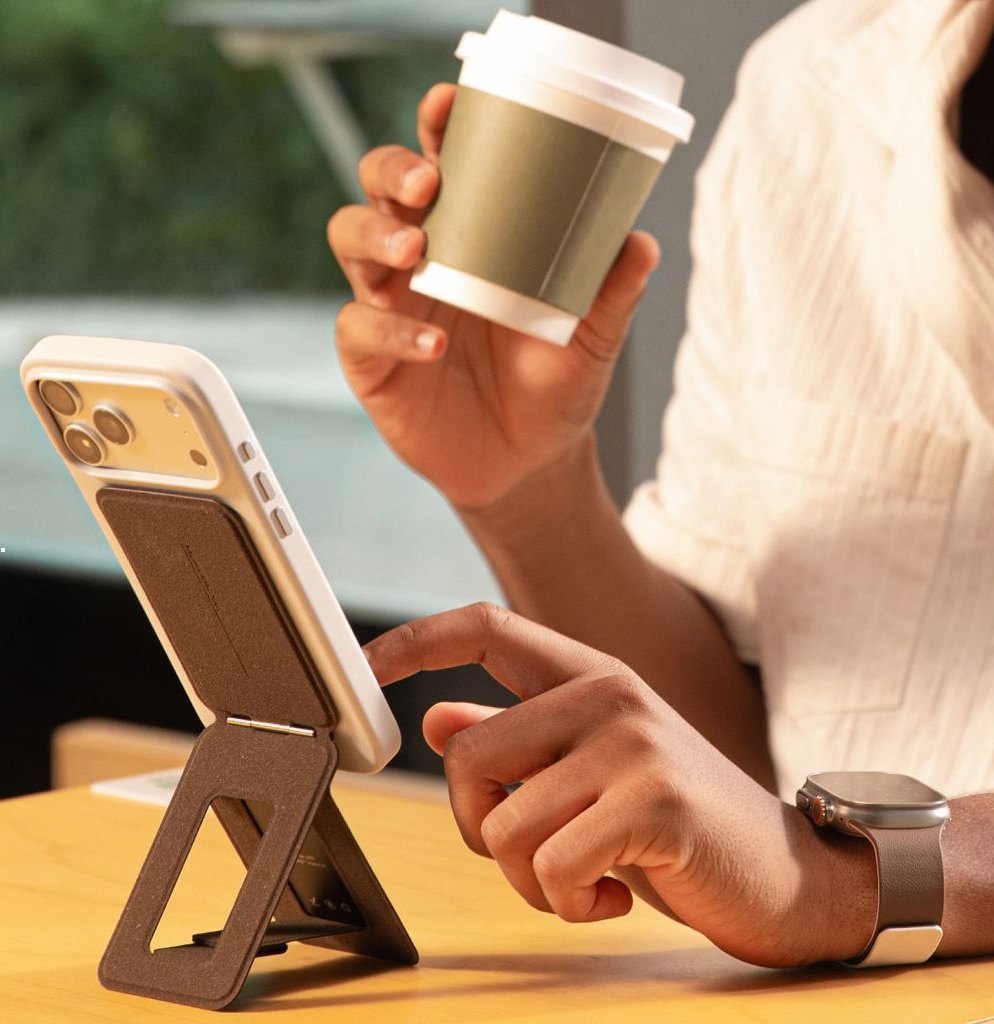iPhone стоит на подставке Snap Invisible Tripod Stand MOVAS-E, рядом рука с чашкой кофе