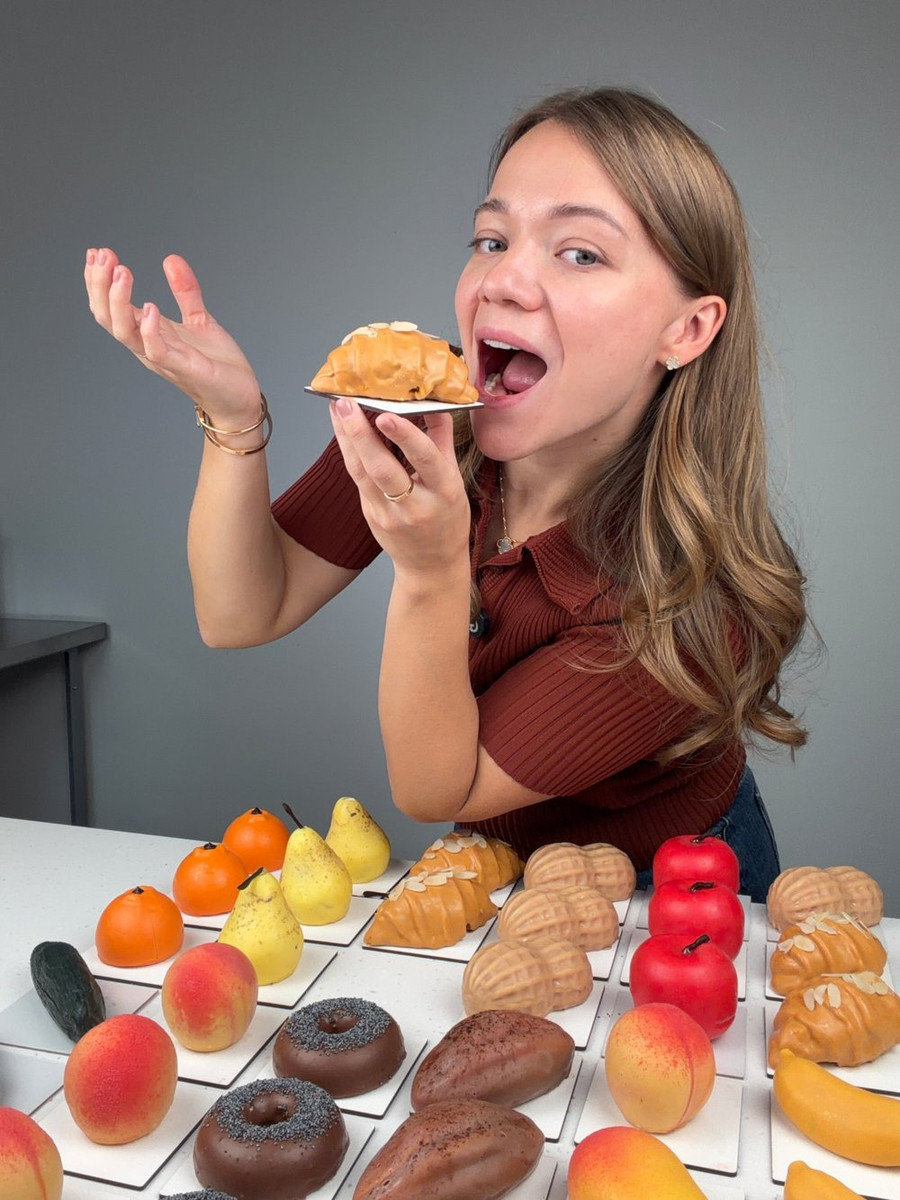 Анастасия Лазарева пробует корпусный круассан, перед ней стол с новыми вкусами