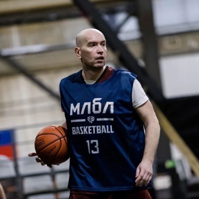 Пётр Гусятников в синей майке МЛБЛ с мячом в руке на площадке