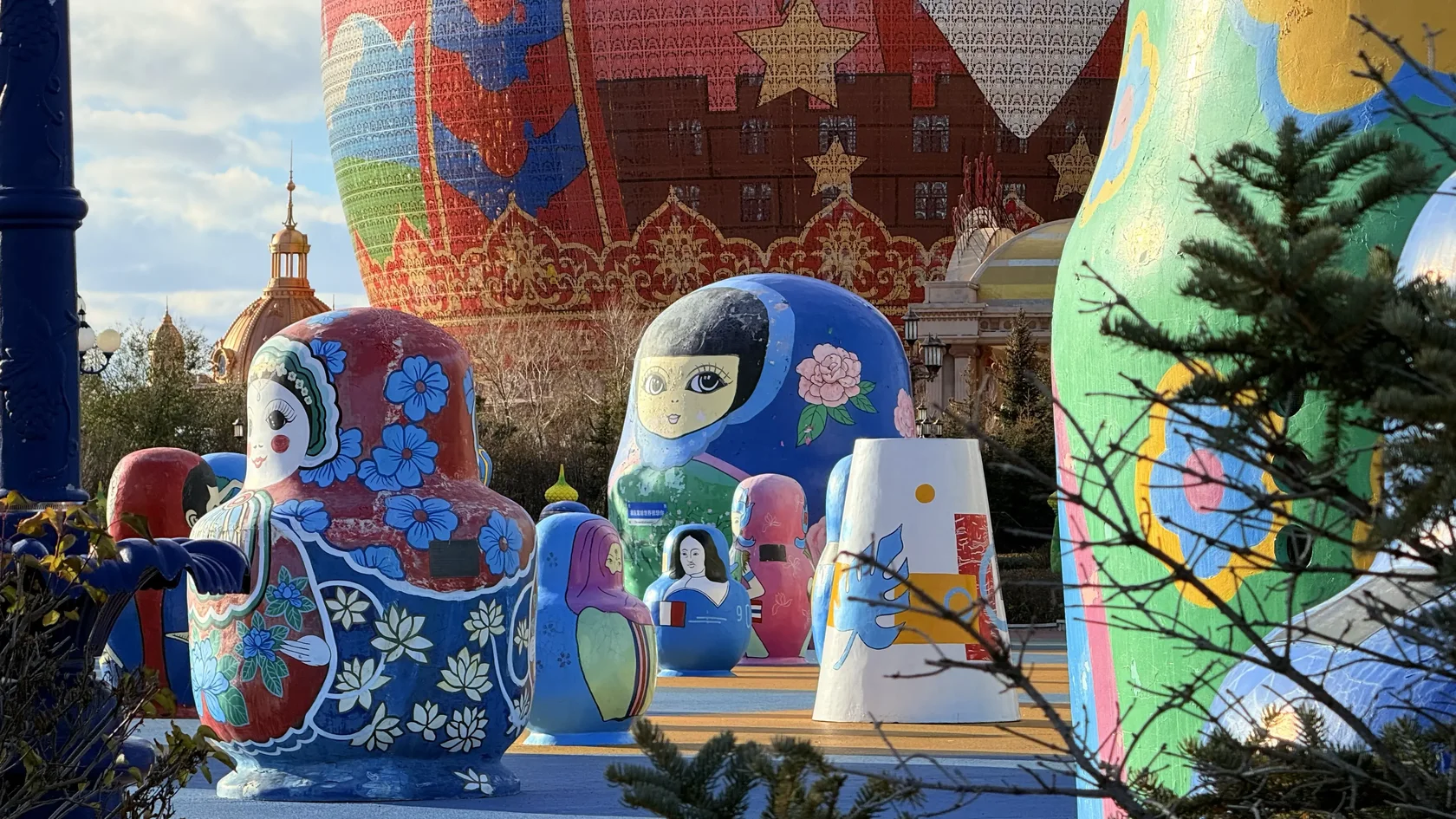 Небольшие расписные Матрёшки перед большим зданием-матрёшкой