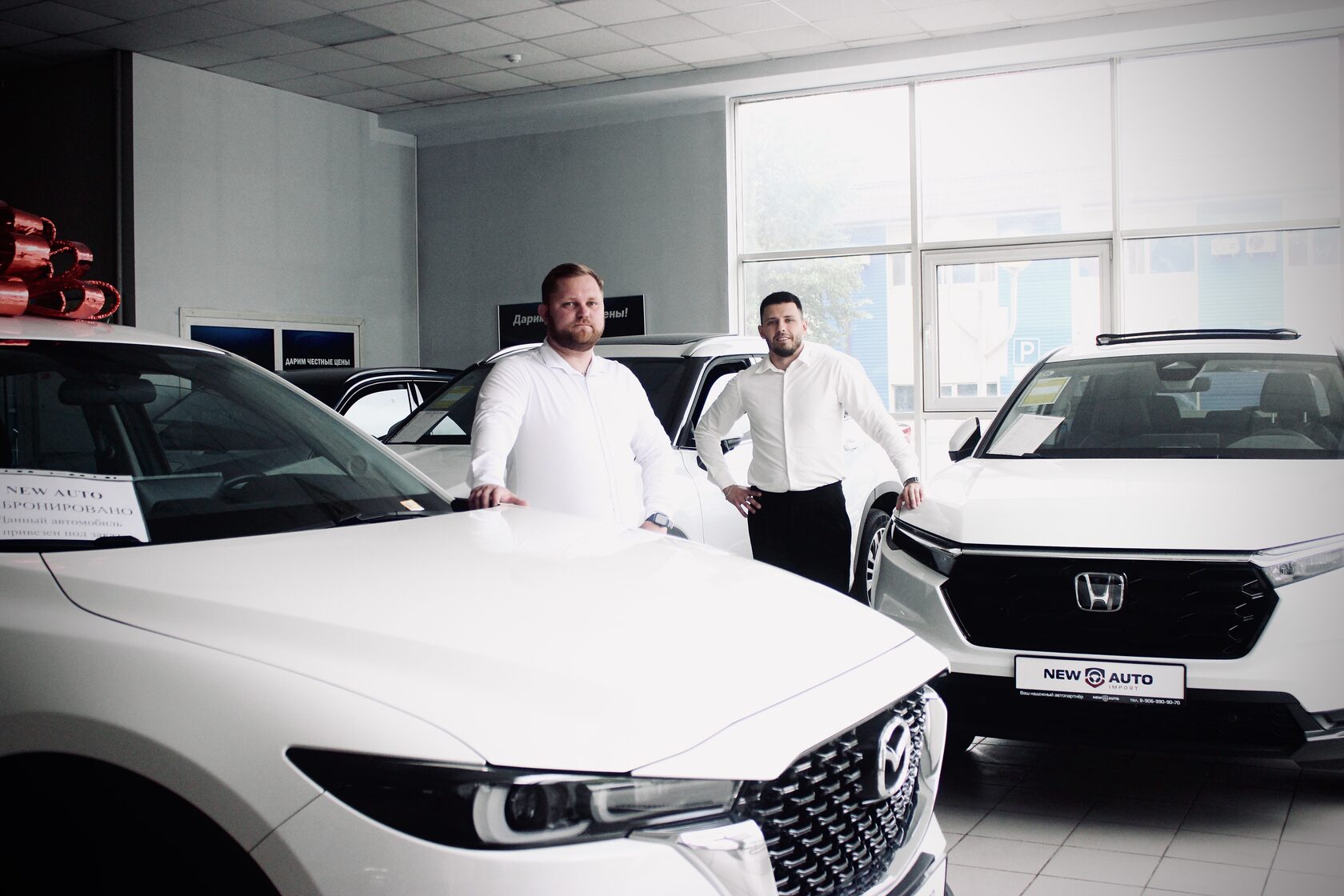 Сотрудники New Auto в нашем тюменском салоне рядом с автомобилями Mazda и Honda