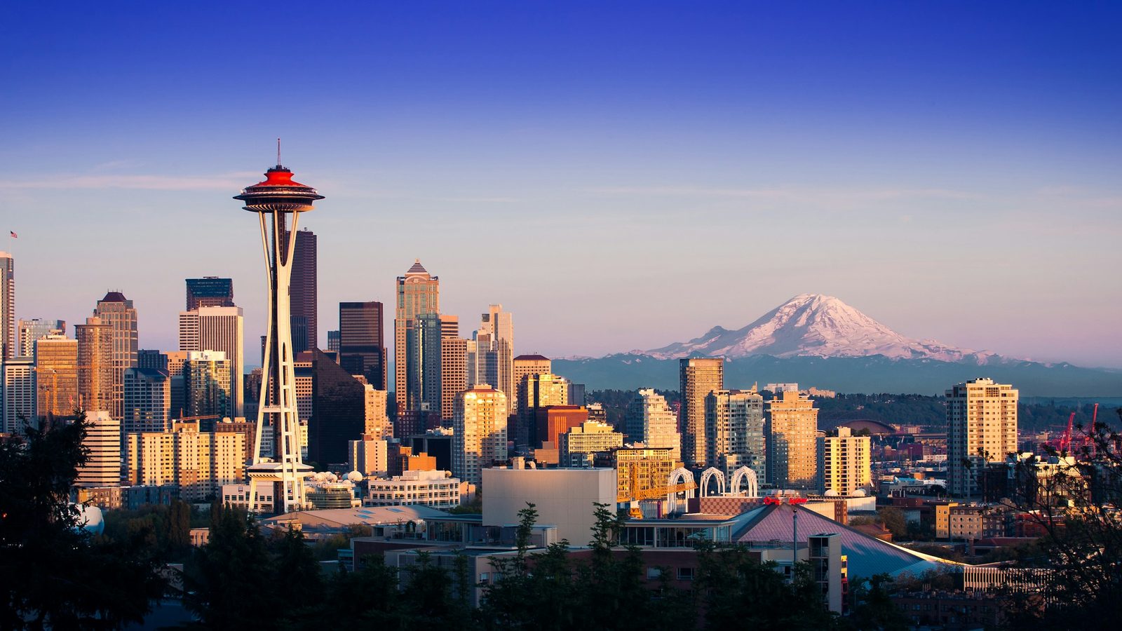 The Space Needle and the Seattle skyline in evening light, with snow-capped Mount Rainier in the distance