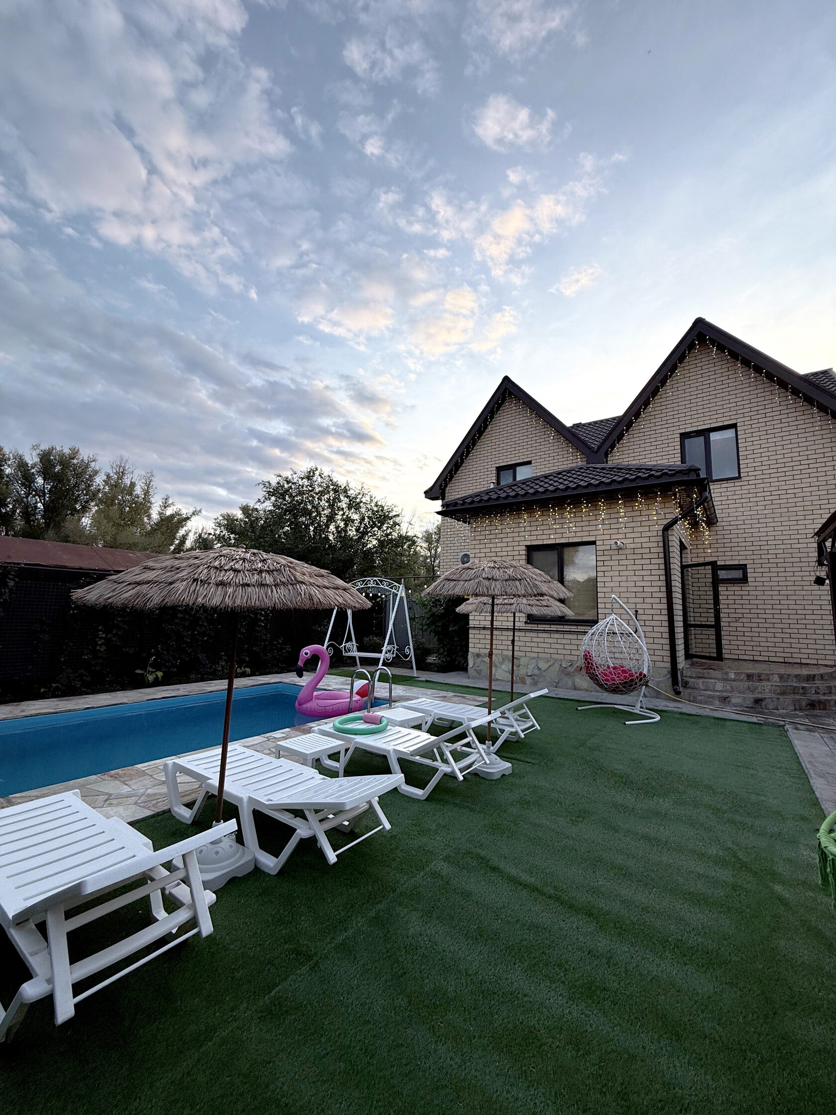 Зона отдыха у бассейна с плетёными зонтами и белыми шезлонгами