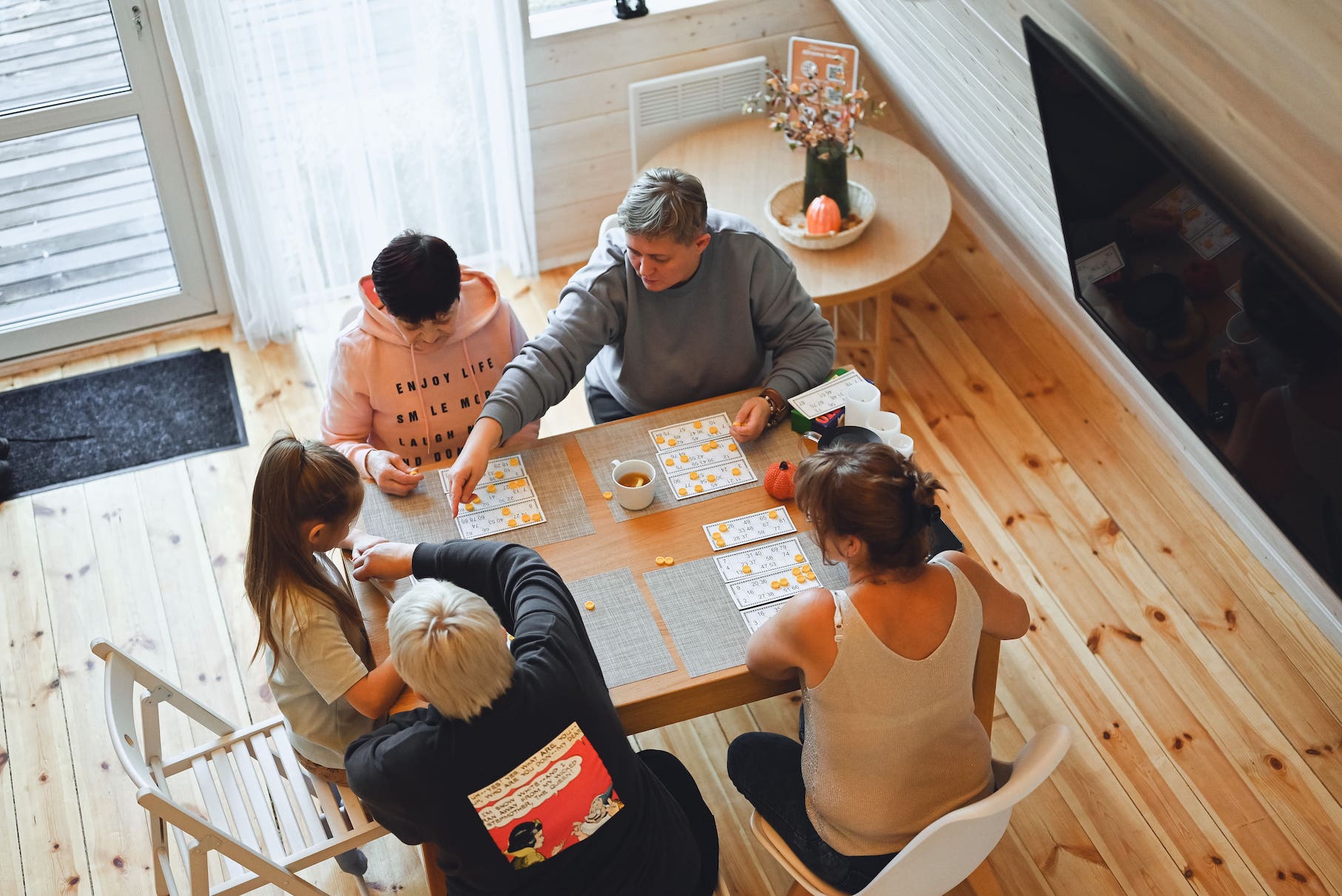 Семья за настольной игрой в уютном интерьере треугольного домика - идея для зимней традиции