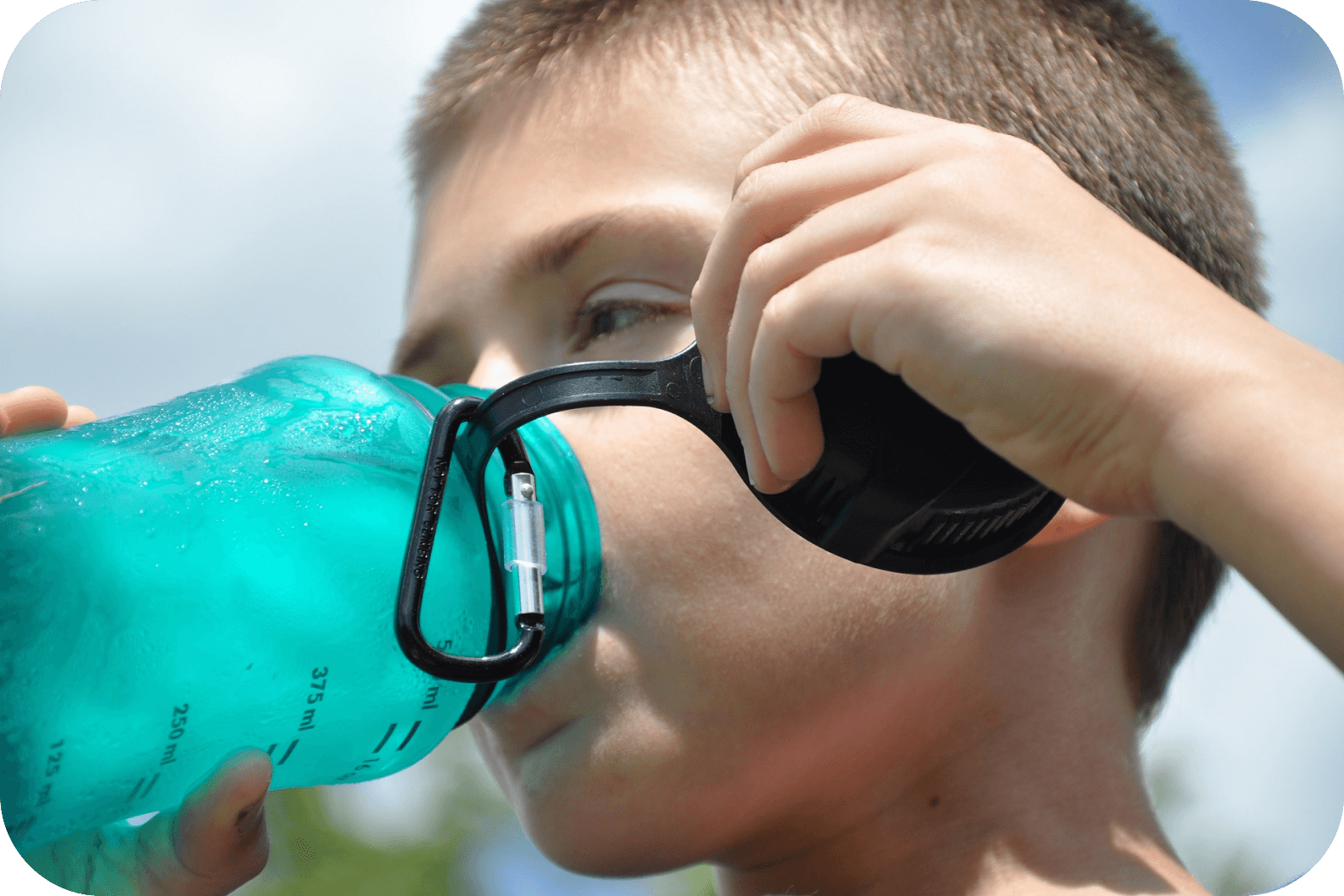 Мальчик пьет чистую воду из бутылки
