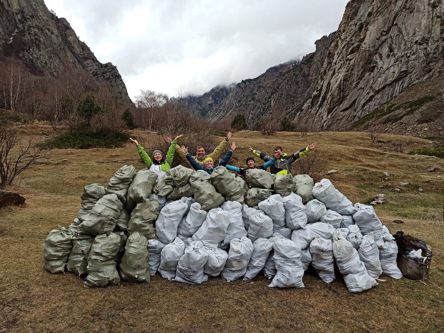 Volunteers lying on a big pile of collected rubbish sacks in a mountain valley