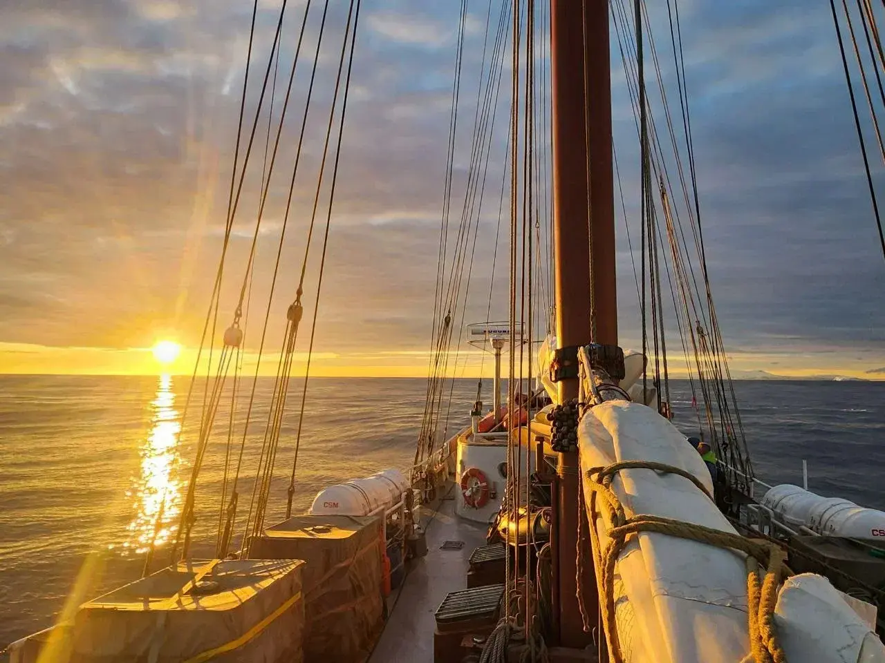 Sailing expedition to Antarctica at sunset with a view from the deck of a sailing ship crossing the Southern Ocean