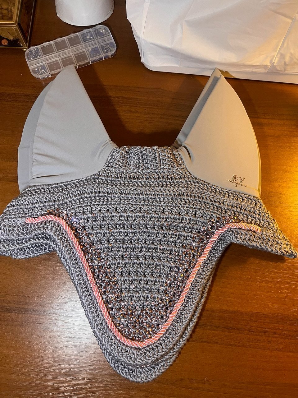 Grey hand-knitted ear bonnet with pink edging.