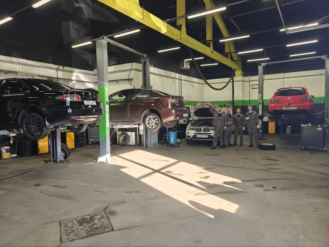 Рабочий бокс Bring Auto с командой мастеров и автомобилями на подъёмниках