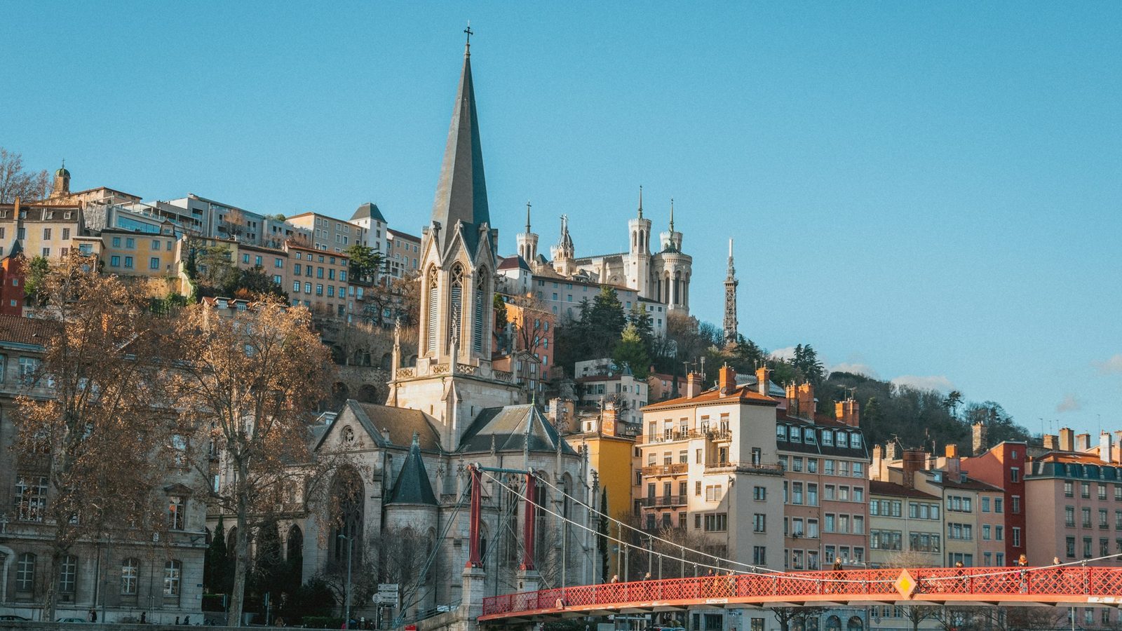 Saint-Georges church and the red Saint-Georges footbridge over the Saône in Lyon, with the Basilica of Notre-Dame de Fourvière on the hill behind