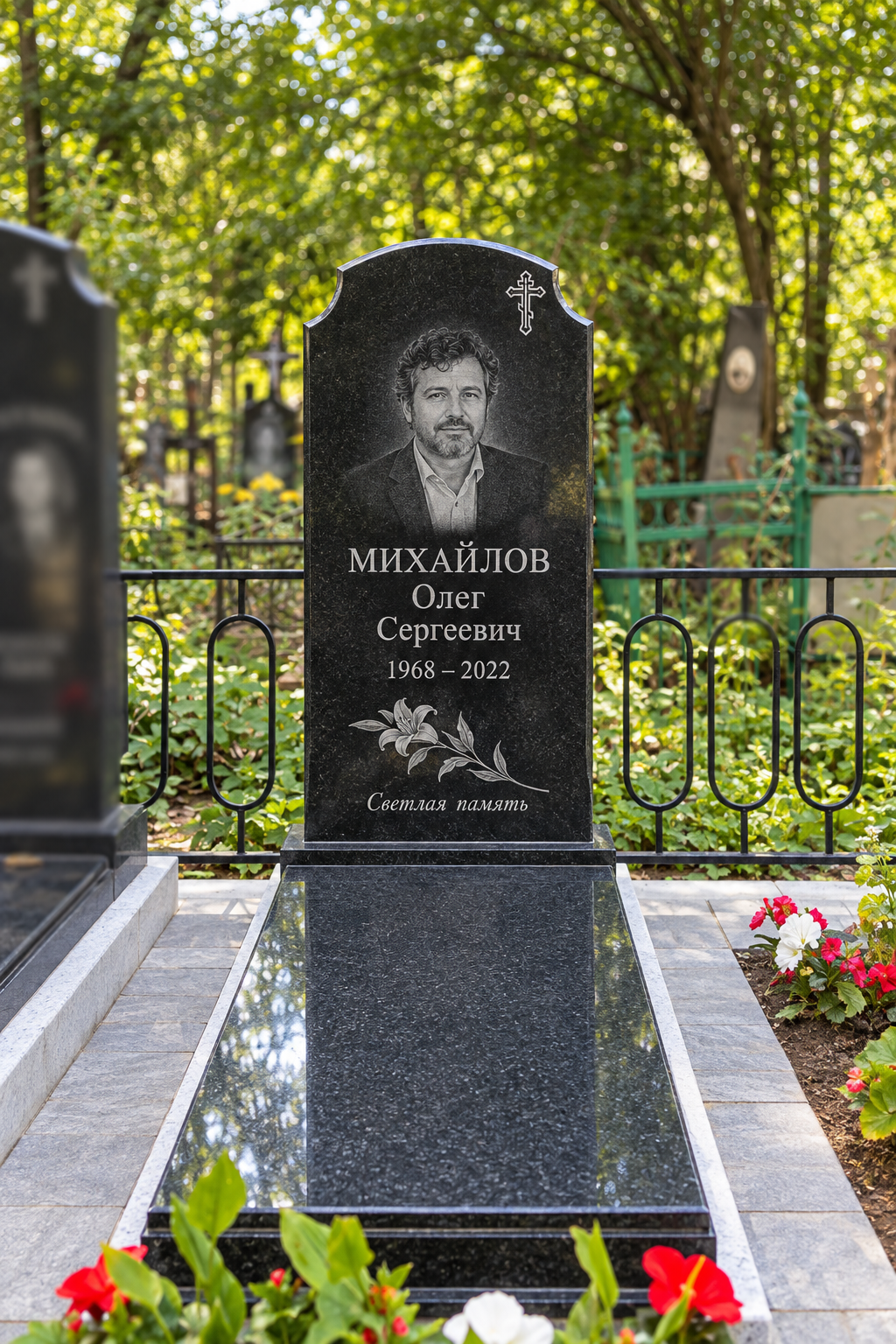 Фигурная стела с закрытым цветником после установки на участке. Имена, даты и портреты изменены.