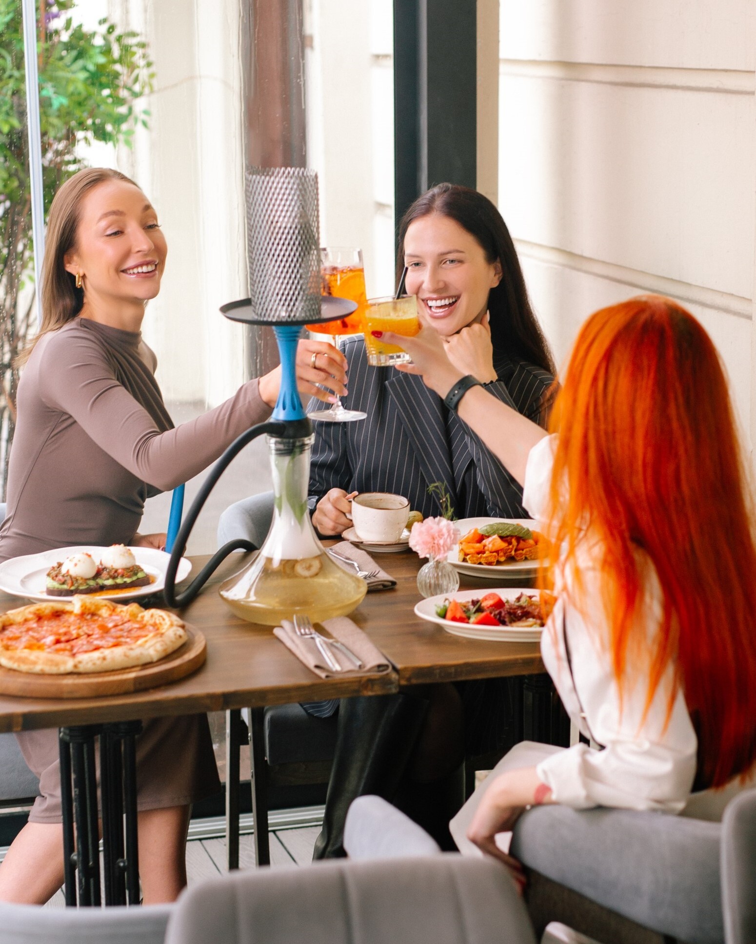 Акция Galentine's Day: компания подруг улыбается за столом с коктейлями в ресторане HYPE. Скидка на напитки для женских компаний.