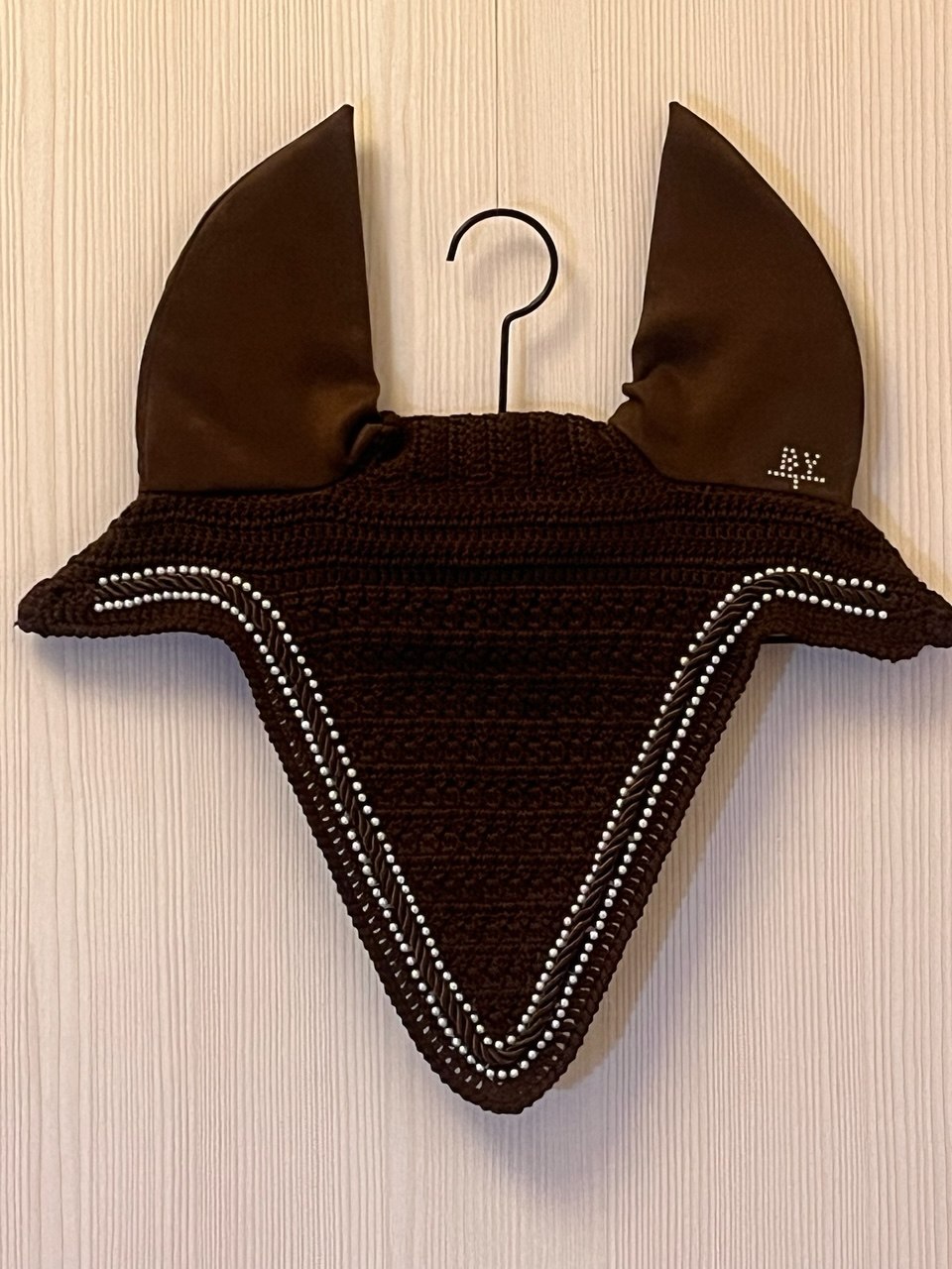Hand-knitted wholesale ear bonnet in brown with pearl edging.