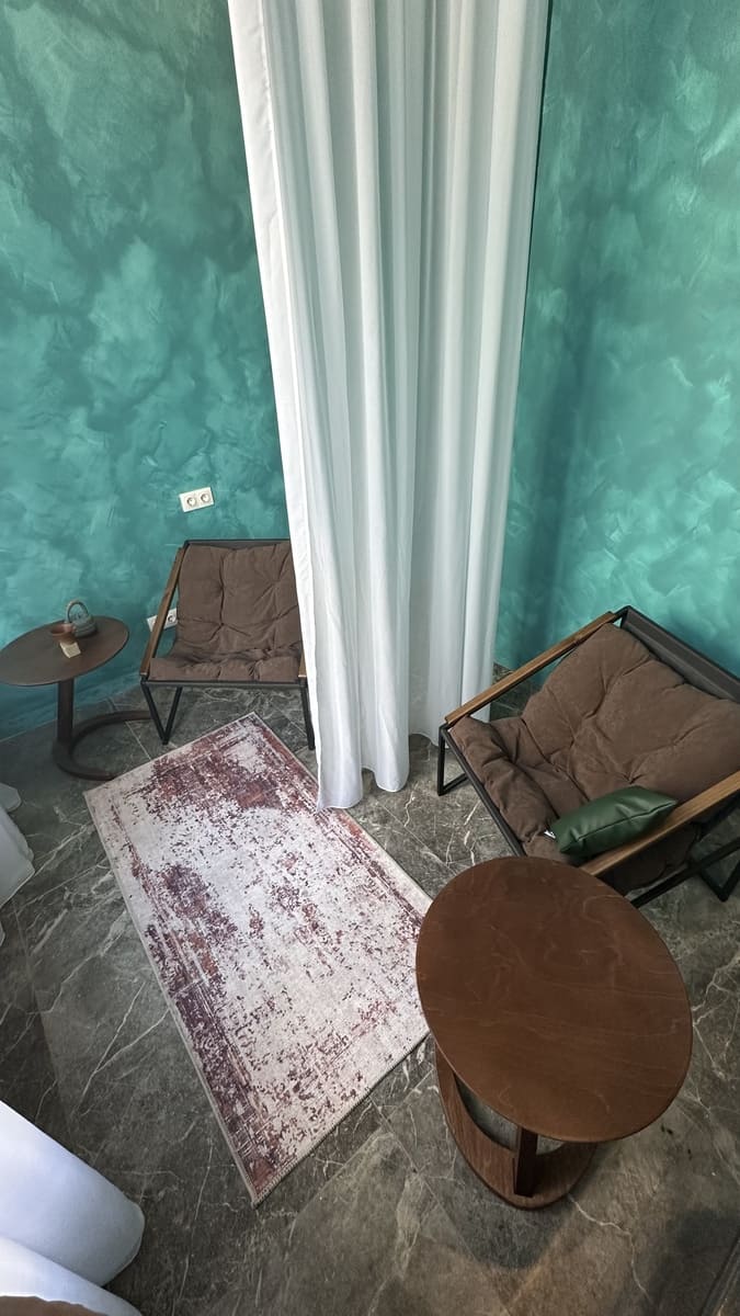 Зона отдыха на две персоны в студии ПАУЗА. Пространство разделено легкими тюлями, с ковром и удобными креслами для уединения.