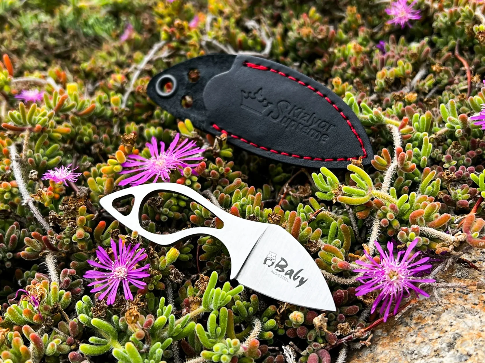 Kizlyar Supreme Baby miniature fixed blade and leather sheath among flowers