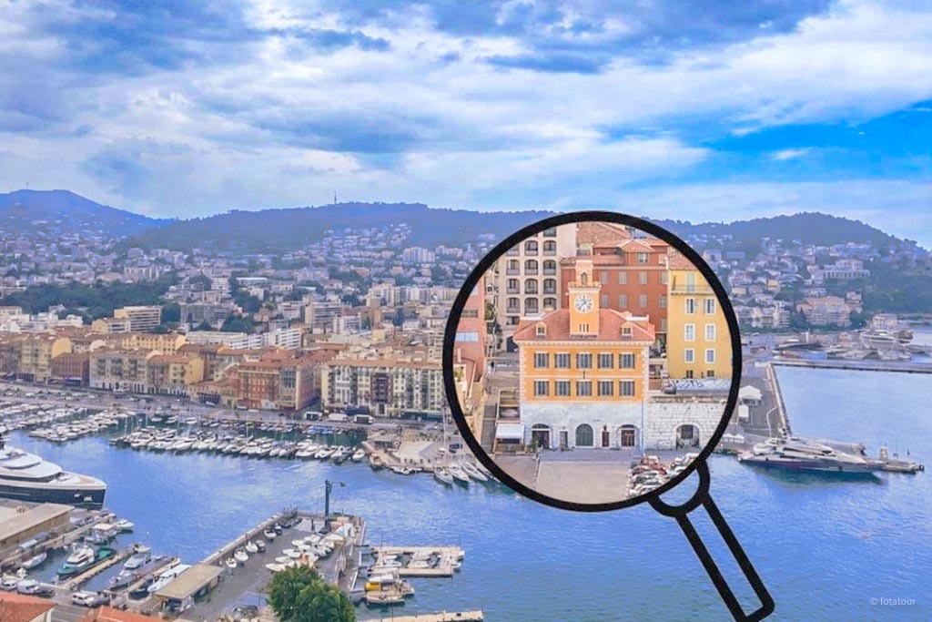Aerial view of the Port of Nice: the Espace Lympia building with its clock, surrounded by yachts, the waterfront, and the city hills
