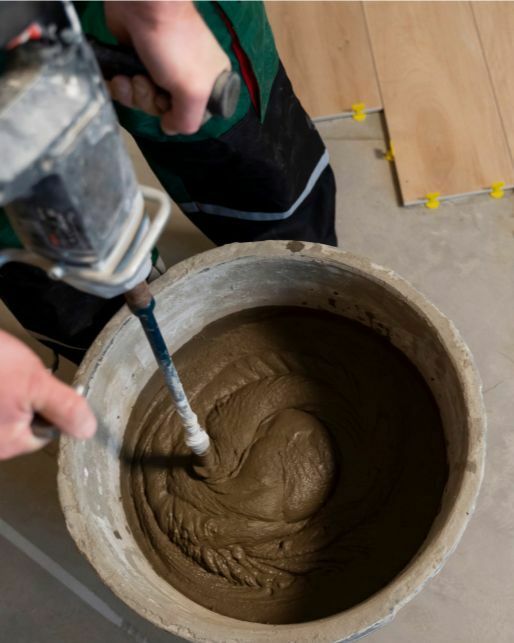 Строитель замешивает строительным миксером сухую строительную смесь Квик Микс от официального дилера ТрейдМикс