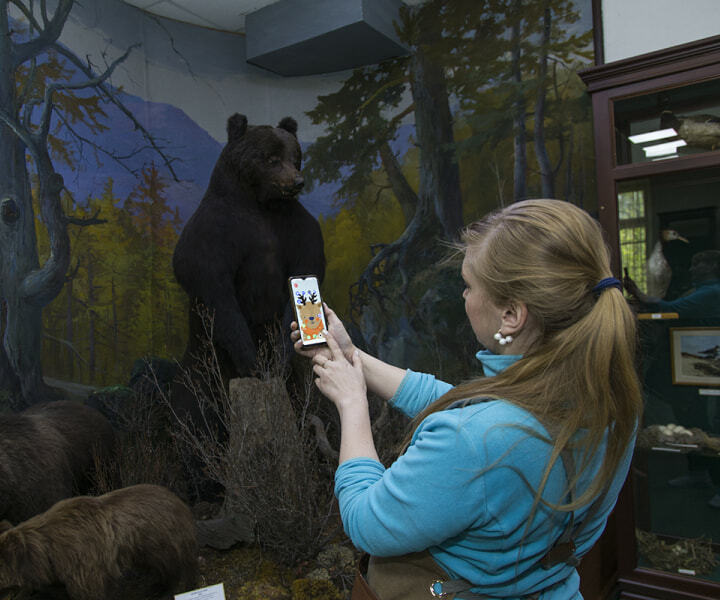 Посетительница фотографирует на телефон чучело медведя