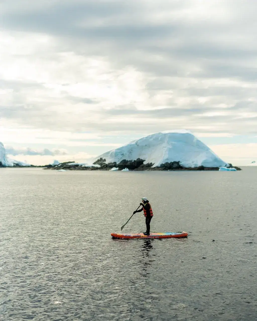 Person paddleboarding among Antarctic icebergs during a small-group sailing expedition in Antarctica