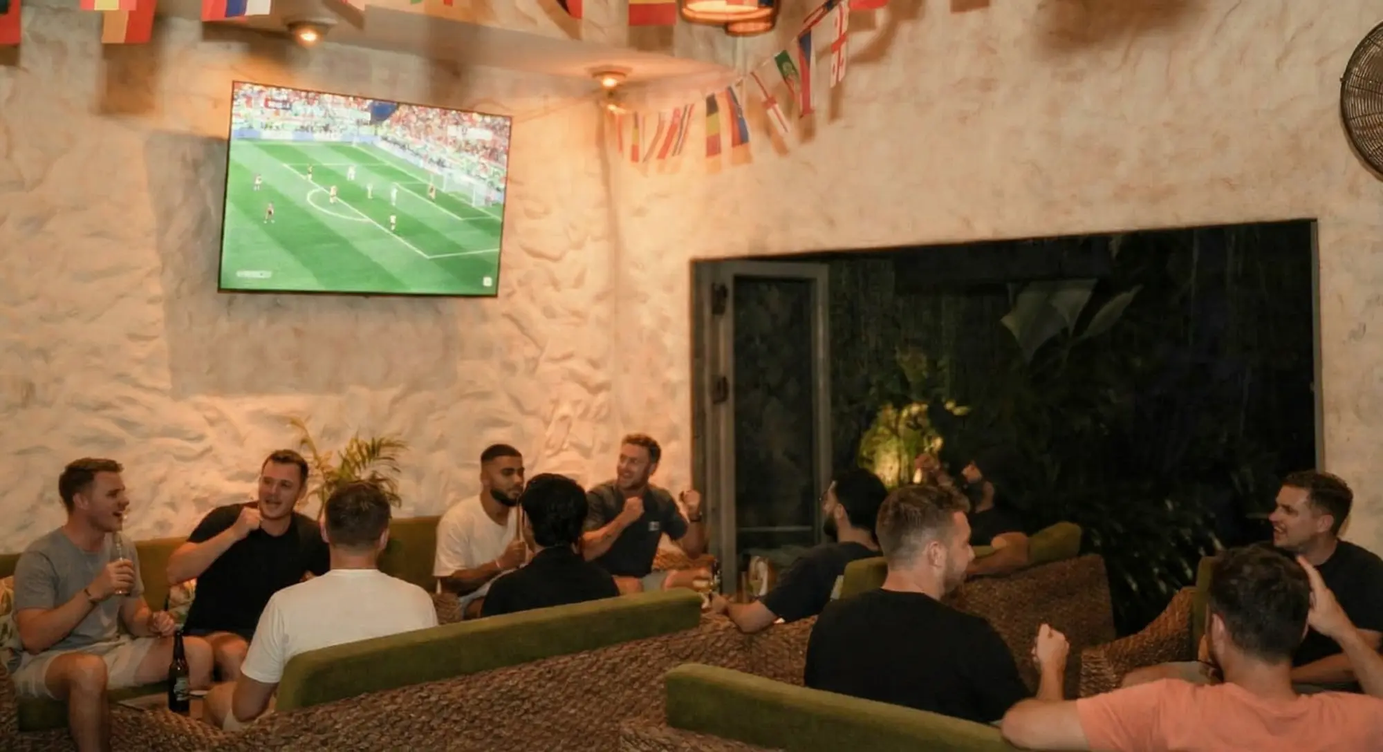 Group of friends watching a live football match at Eden Sports Bar Seminyak with a big screen and comfortable seating.