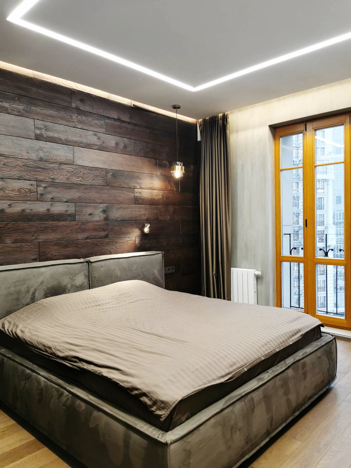дерево на стене, серая кровать, деревянный пол, линейный светильник