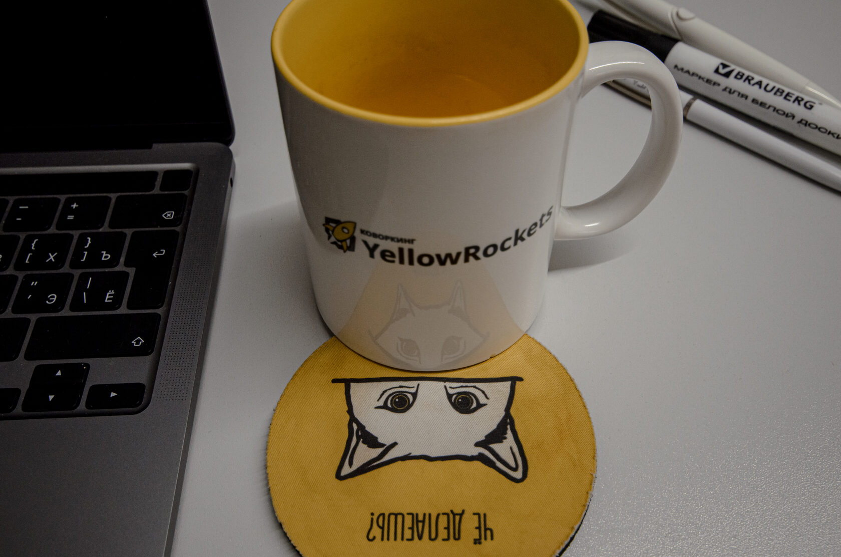 Фирменная чашка Коворкинга YellowRockets рядом с ноутбуком