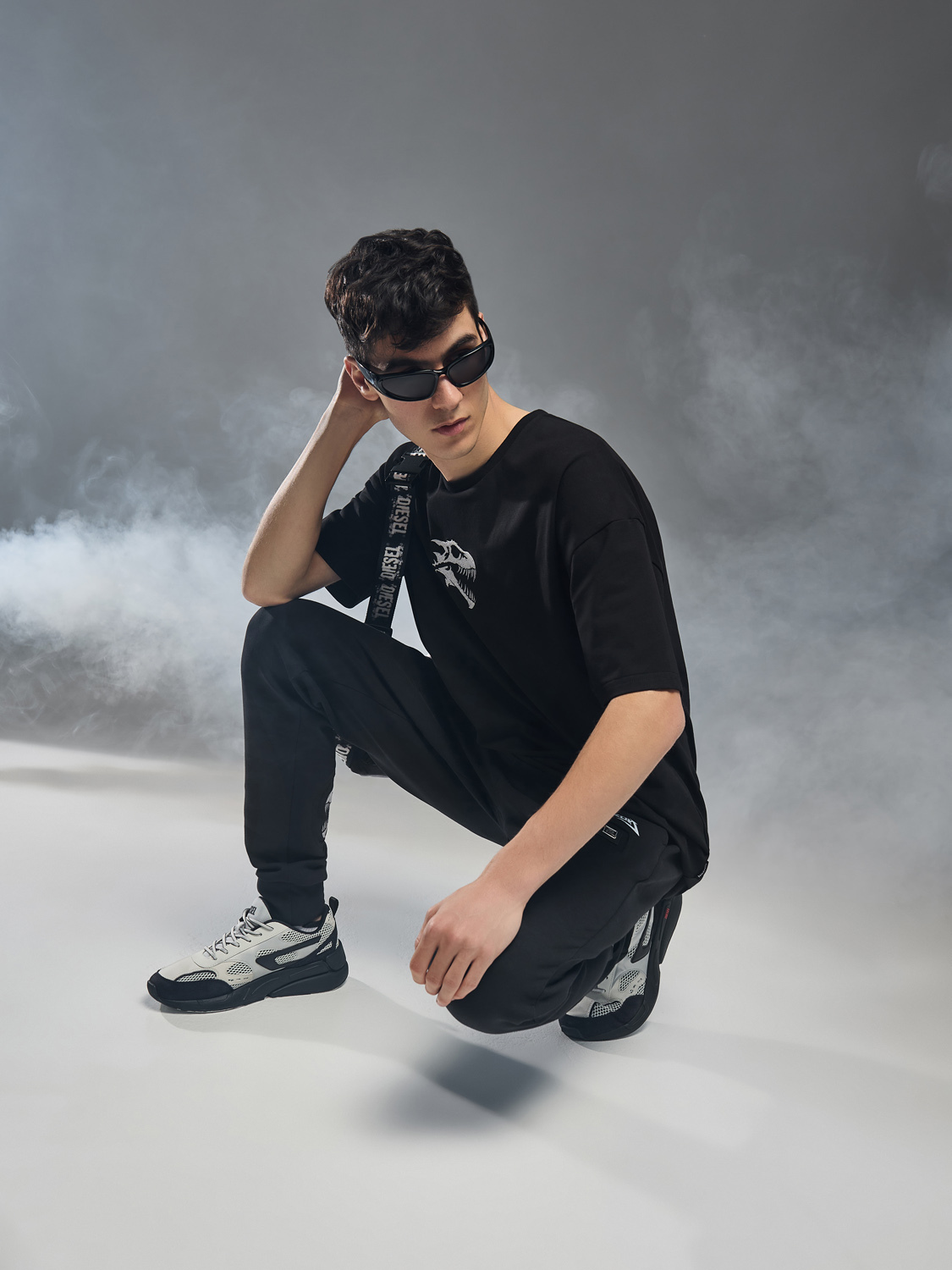 мужчина в черном спортивном костюме на корточках в студии