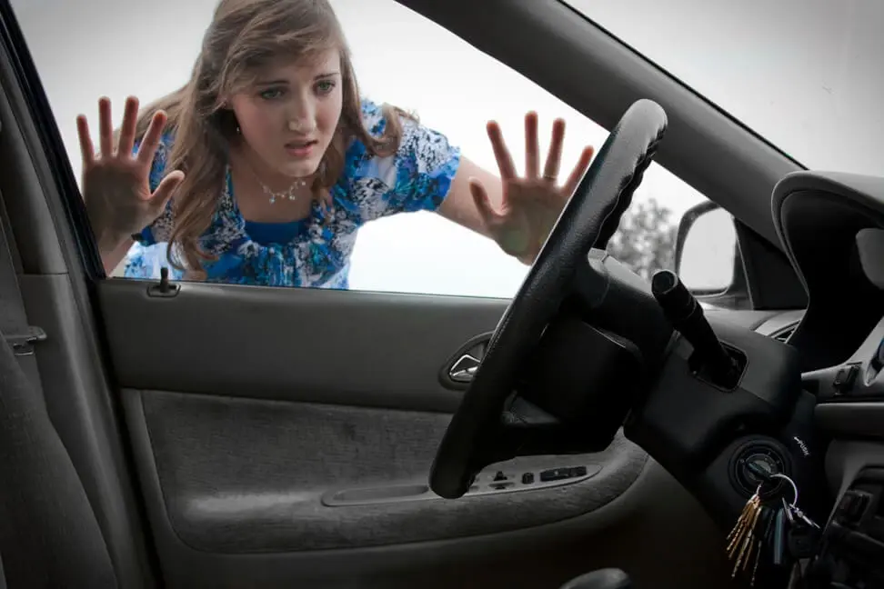 Woman locked out of her car looking through the window with keys inside, needing emergency car lockout service