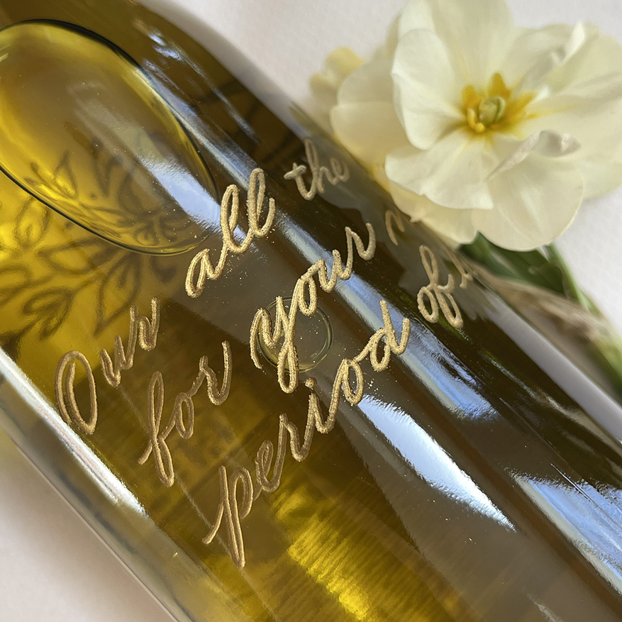 Luxury custom wine bottle with fine gold lettering and a white flower.