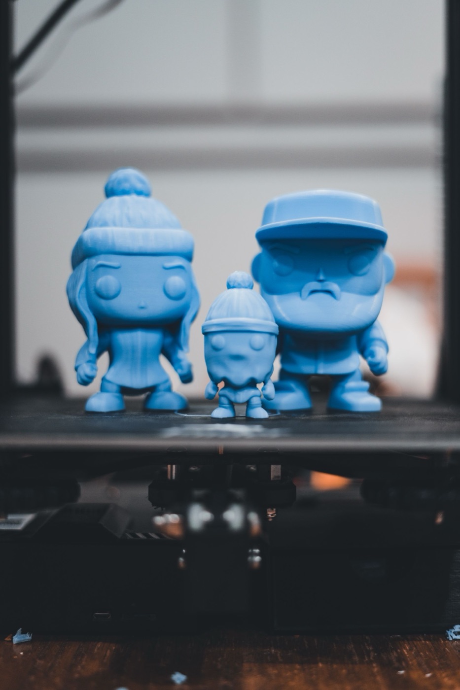 Три синие фигурки на столе 3D-принтера