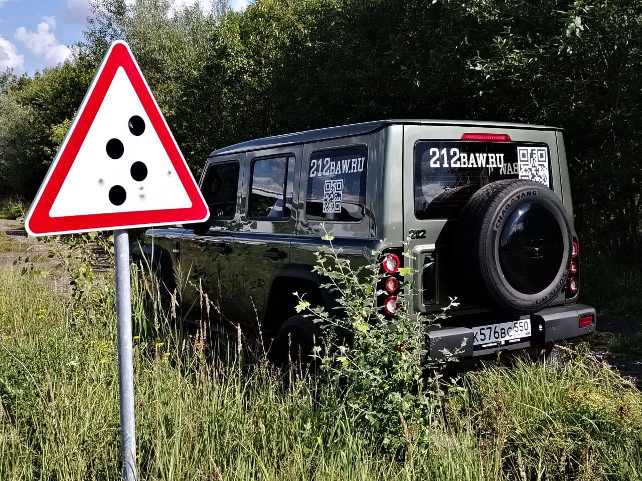 212 T01 на неровной дороге внедорожного полигона рядом со знаком падения камней