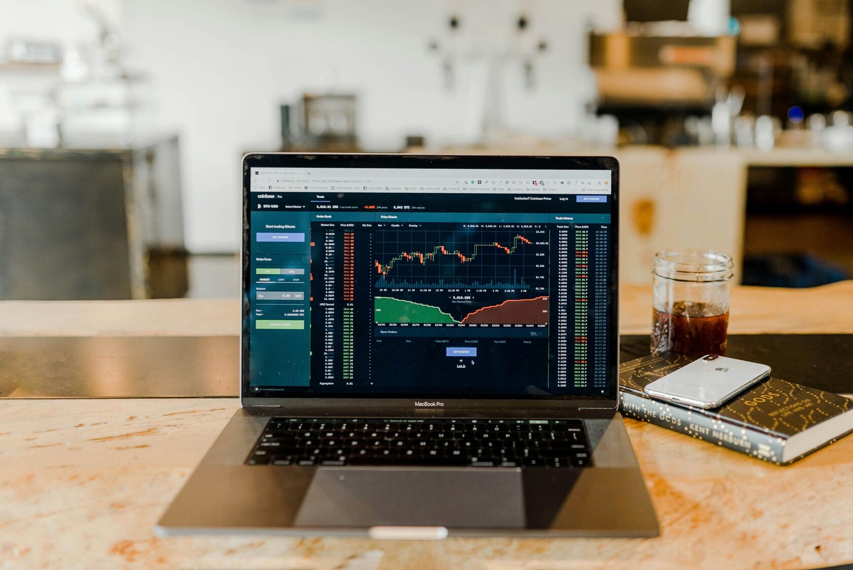 Professional trading workspace featuring a laptop with real-time candlestick charts and financial market analysis tools.