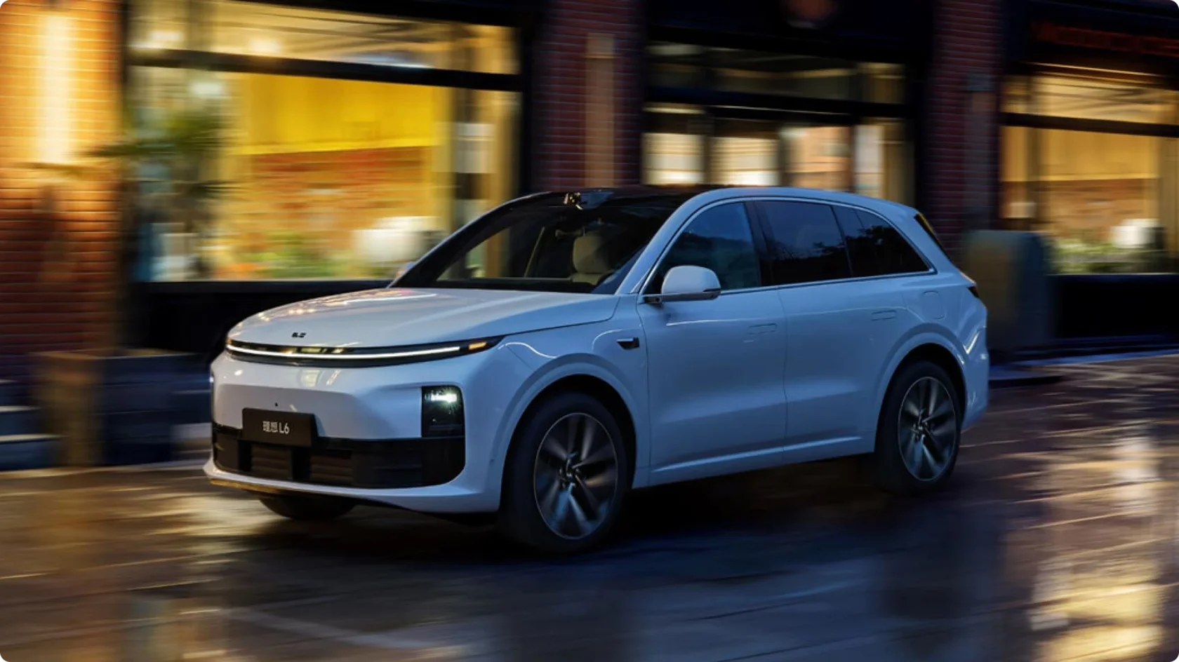 Ли Auto L6 в белом цвете в динамике на ночной улице после дождя, светодиодная полоса ярко горит, вид спереди сбоку с эффектом размытого фона.