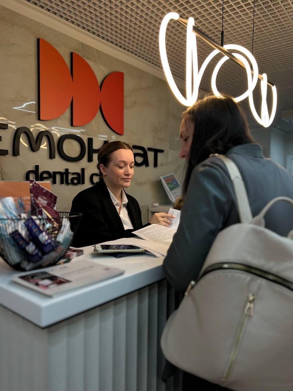 Администратор клиники Demokrat принимает пациента на ресепшене