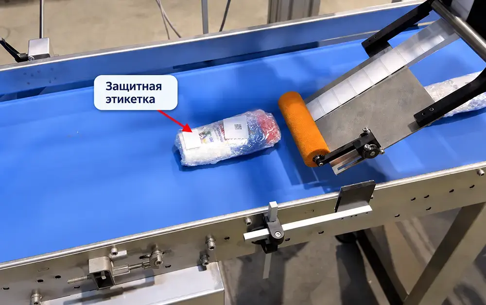 Аппликатор наносит белую этикетку поверх исходного штрихкода товара после термоусадочной упаковки