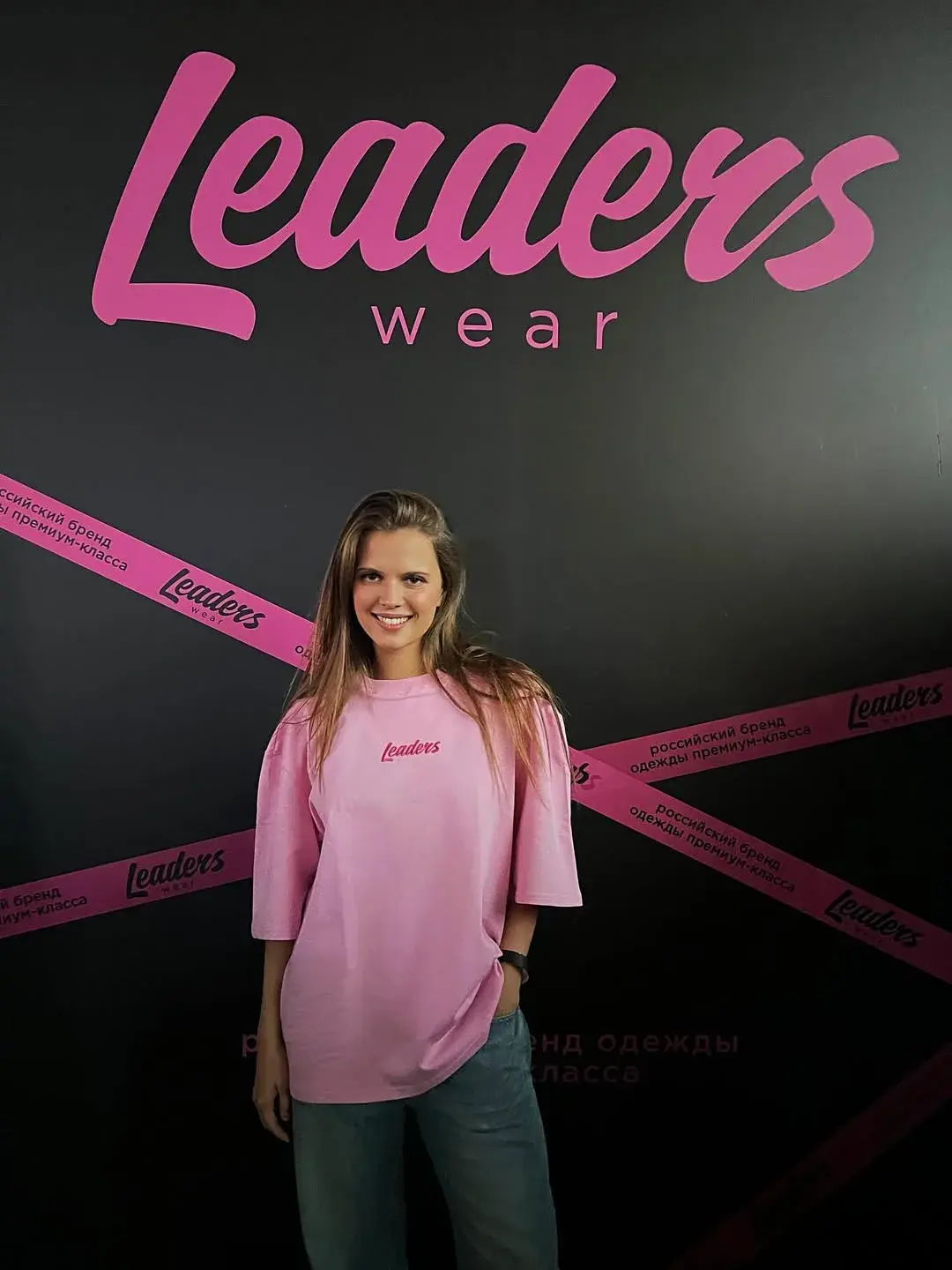 Участница в розовой футболке Leaders Wear на брендированной площадке.